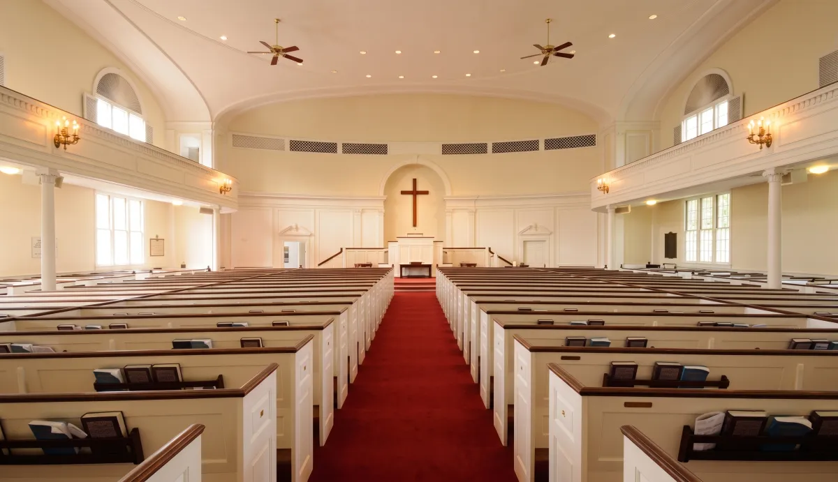 Church sanctuary interior with wood pews and a center aisle