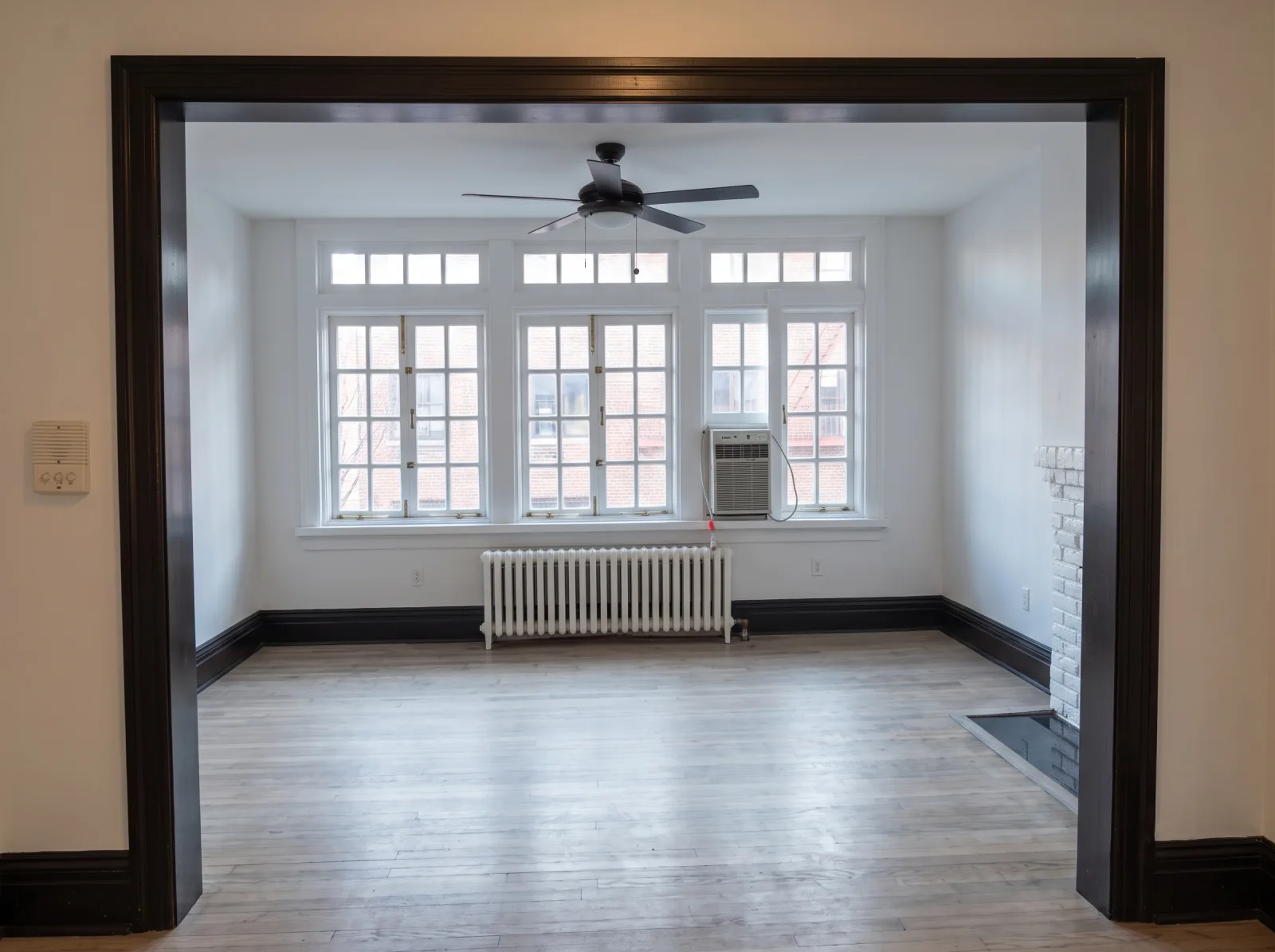 Freshly painted white living room with a whitewashed brick fireplace in Manhattan