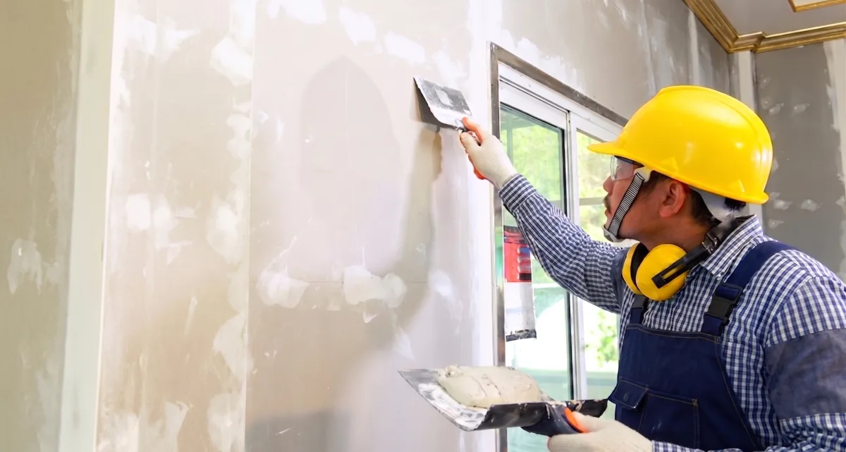 Contractor skim-coating a drywall patch before painting